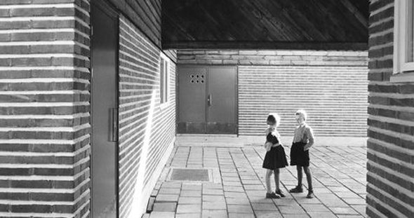 Kaksi lasta rakennuksen laatoitetulla sisäpihalla.