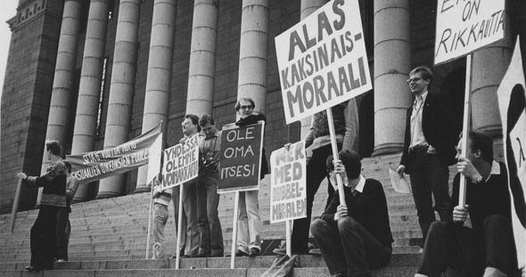 SETA 6-vuotta -mielenosoitus Eduskuntatalon portailla. Kylteissä lukee mm. "Erilaisuus on rikkautta!", "Alas kaksinkaismoralismi", "Ole oma itsesi"