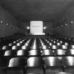 Interiöörikuva Jyväskylän suojeluskuntatalon elokuvateatterista. Valokuva on otettu valkokankaalta yleisöönpäin, sali on tyhjä.