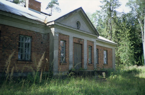 Eksteriöörivalokuva Mäntsälän seurantalosta. Metsittynyt rakennus on tyyliltään uusklassistinen.