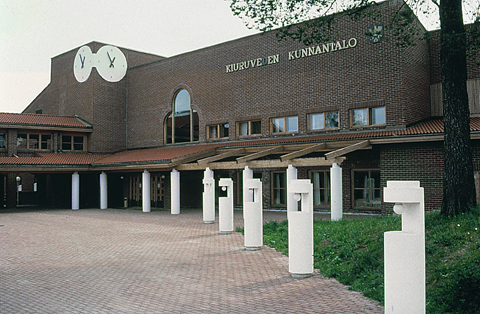 Eksteriöörikuva Kiuruveden Kunnantalosta. Rakennus on punatiilinen ja sen edustalla on laatoitettu aukio.