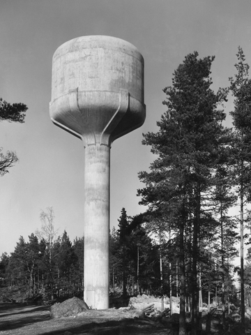 Eksteriöörikuva Loviisan vesitornista. Mäntyrinteeseen sijoitettu vesitorni on betoninen ja muodoltaan muistuttaa valtavaa marakassia.